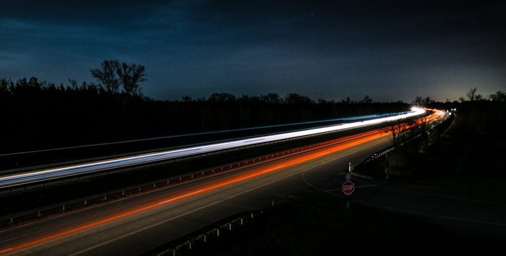 Contactar Transporte Ferreira Camarena Long exposure shot capturing vibrant light trails on a highway at night.